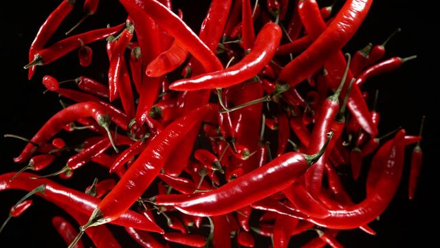 Super Slow Motion Shot of Flying Fresh Chilli Peppers Isolated on Black Background at 1000 fps.