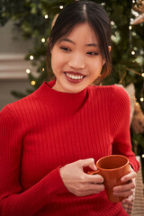 Cheerful woman smiling toothy while sitting at the sofa with cup of tea