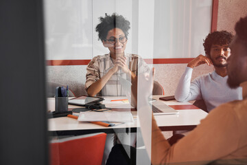 Fototapeta premium Kind dark-skinned manager keeping smile on her face while listening her colleagues
