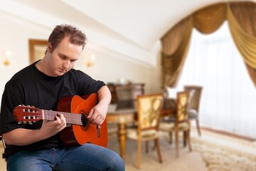 Obraz premium Lifestyle concept. Young musician playing guitar in the living room at home on this weekend.