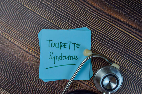 Tourette Syndrome write on sticky notes isolated on Wooden Table.