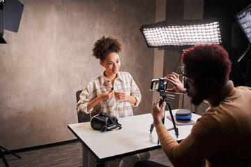 Stylish man helping recording video blog to his female friend