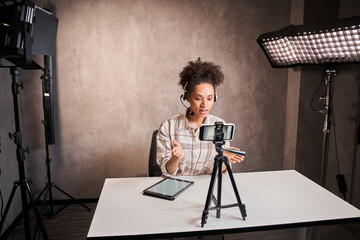 Young mixed race blogger woman with curly hair looking at webcam and talking to camera