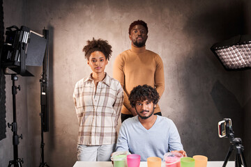 Multiracial people looking at camera while preparing broadcasting blog with kinetic sand