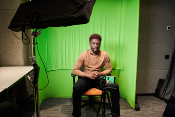 Multiracial man sitting at the chair in front of the smartphone on the tripod