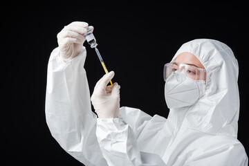 immunologist in personal protective equipment holding syringe and covid-19 omicron variant vaccine...