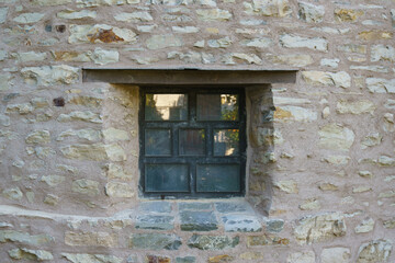 A small window in the thick stone wall of an old antique building.
