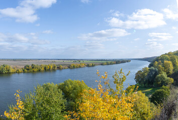 Autumn landscape with a view of the river and endless expanses of fields. Panoramic landscape with river and field and trees.