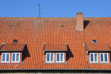 Three dormer windows with tides in a house with a tiled roof. Against the background of the blue sky.