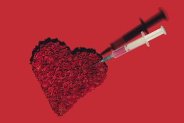 Red frizzle paper heart stabbed with syringe on red background. Valentine minimal concept.