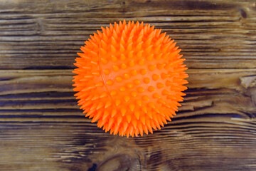 Naklejka premium Orange toy ball. Dog toy for teeth cleaning on a wooden background