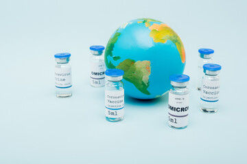 covid-19 omicron variant vaccine bottles near globe on blue background.