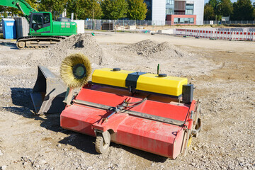 Street sweeper machine and green exavator on construction site.