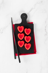 Small mousse cake in the shape of a red heart with jelly filling on a serving board. Top view. Valentine's Day