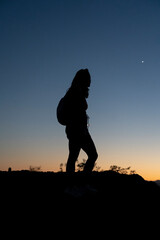 The silhouette of a female hiker at sunset