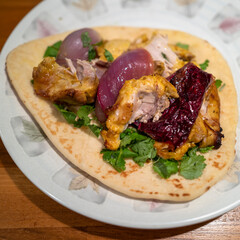 Preparing chicken Souvlaki Greek dish on pita with onion and vegetables