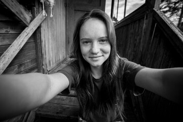 A girl takes a selfie in the farm house. Black and white photo.