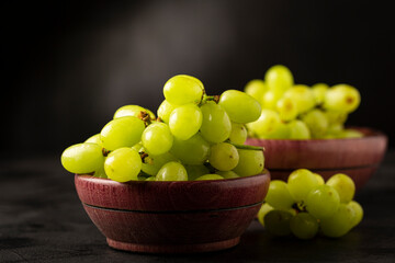 Fresh green grapes in wooden bowl.