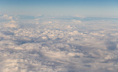 Stratosphere, a view of clouds from an airplane window.  Cumuliform cloudscape on sky. Flying over the land.