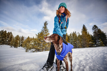 a young woman and her dog snowshoeing on a mountain trail