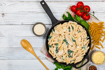 Chicken Alfredo Parmesan Penne Pasta with Spinach on White Wooden Background Top View. Selective focus.