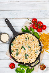 Chicken Alfredo Parmesan Penne Pasta with Spinach on White Wooden Background Top View. Selective focus.