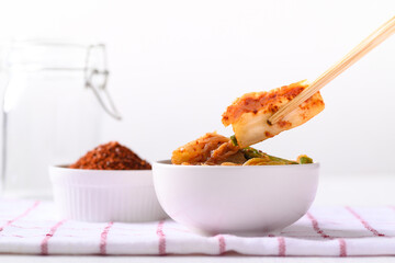 Kimchi cabbage in a bowl eating by use chopsticks on white background, Korean homemade fermented side dish food