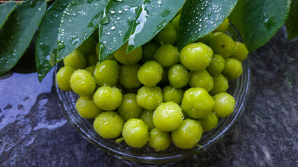 close up of ceremai or Phyllanthus acidus isolated on a plate and its leaves.