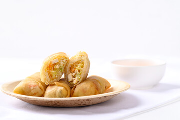 Asian deep fried spring roll filling with tofu, cabbage, carrot and glass noodle on natural plate eating with dipping sauce. Vegan food
