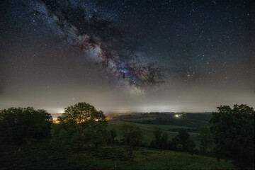 Naklejka na ściany i meble Milky Way over rural landscape with meadow full of trees