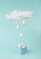 Creative image of eggs falling from a cloud into a blue box.