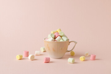 A small beige cup overflowing with small multicolored marshmallows.