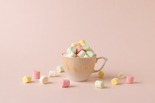 A small beige cup overflowing with small multicolored marshmallows.