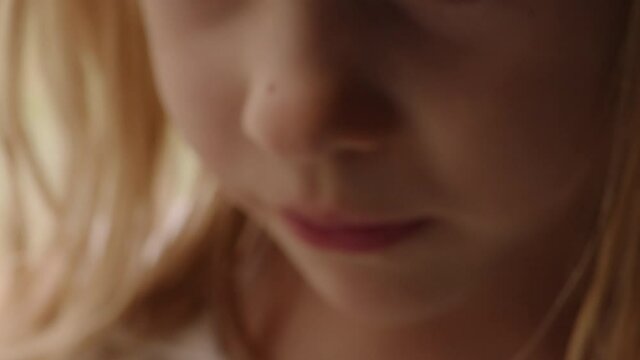 Beautiful slow motion close up portrait of a little girl's face as she looks toward the camera.