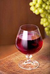 Glass of wine with grape on wooden background
