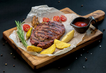 Beef steak with twig rosemary and potatoes on a wooden table.
