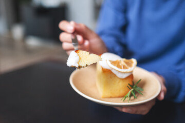 Closeup of a woman holding and eating a piece of lemon pound cake
