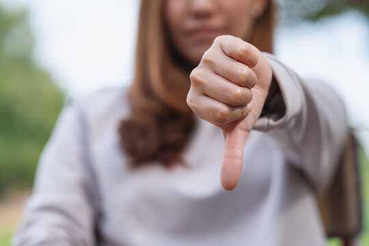 Closeup image of a woman making thumbs down hands sign