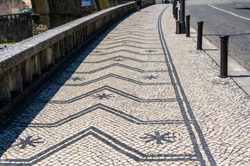 Portuguese pavement mosaic sidewalk with street.