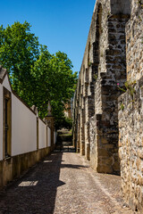 Narrow path with old stone arches, stairs and trees.