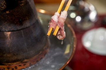 Fototapeta na wymiar A man is eating old Beijing Shabu-shabu mutton, clipping mutton close-up