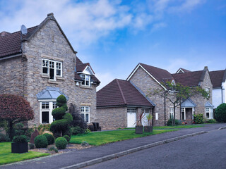 Suburban residential street with two story stone houses with gables and attached two car garage