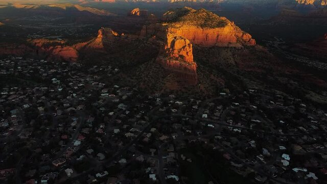 Early morning over Sedona town with bright sunshine on red mountain, aerial drone shot