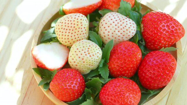 Fresh strawberries in a wooden basket on wooden background, Red Strawberries and white strawberries Pine berry or Hula strawberry in Bamboo basket.