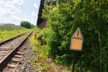 warning yellow sign next to the railroad tracks