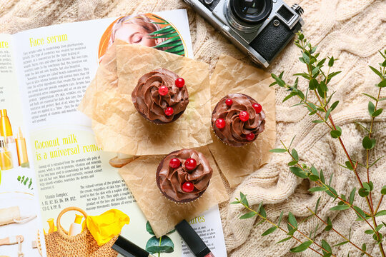 Tasty chocolate cupcakes with fashion magazine and photo camera on sweater