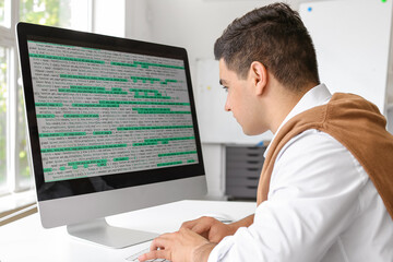 Naklejka na ściany i meble Male programmer working in office