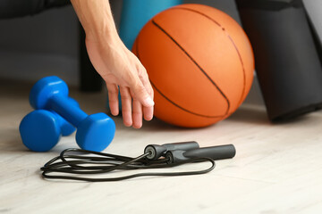 Sporty young man picking up skipping rope from floor, closeup