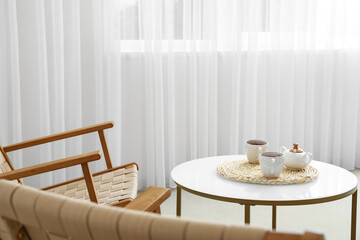 Coffee table with cups and sugar bowl in light living room