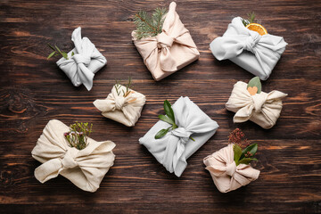 Many gift boxes wrapped in fabric on wooden background